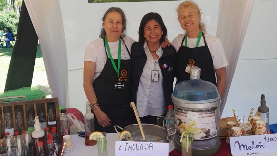 Three women smiling at an artisanal mushroom and liqueur booth at Expo Rural, Cucumén – San Antonio, Chile