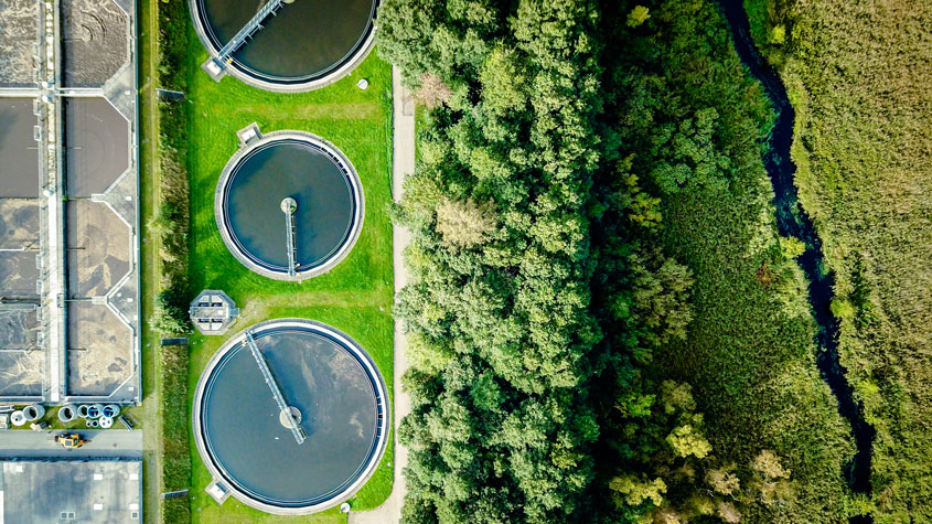 Aerial shot of sewage treatment plant placed near a river.